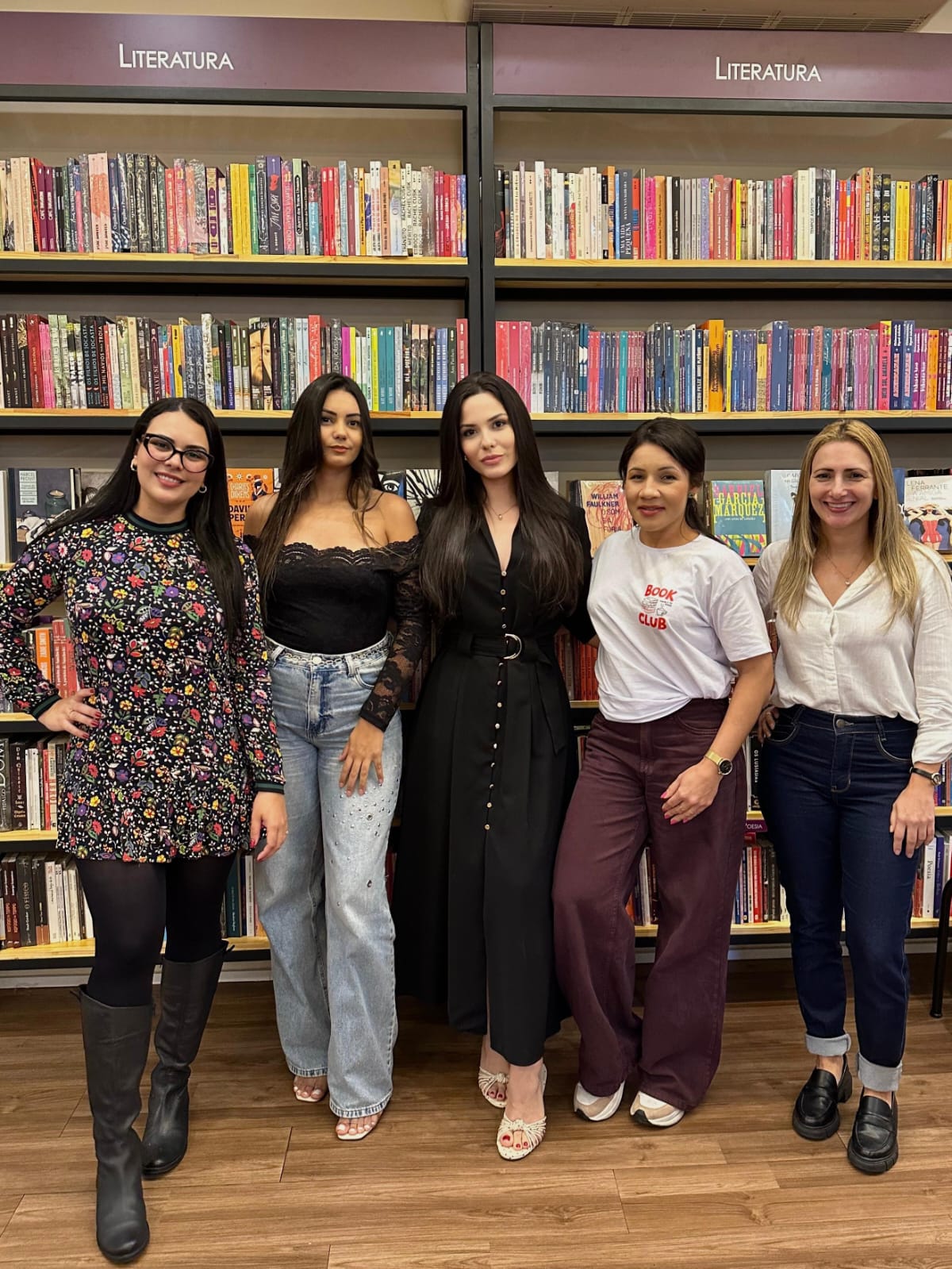 Grupo de mulheres do clube em frente às estantes da livraria